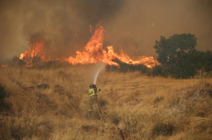 Un pompier tente d'éteindre un feu qui fait rage dans la région de Megara, au nord-ouest d'Athènes, le 3 août 2026.
