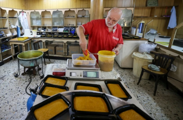 Hassan al-Makari pèse la mfatka dans son échoppe à Beyrouth,  le 29 août 2024 au Liban