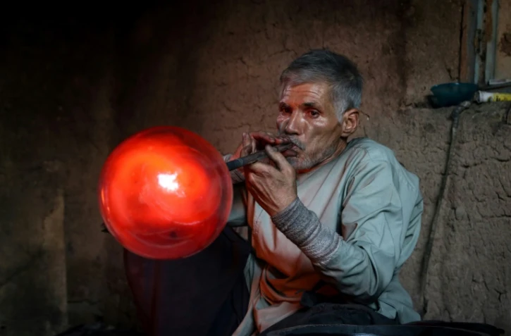 Ghulam Sakhi Saifi souffle du verre en fusion dans son atelier, le 11 août 2024 à Hérat, en Afghanistan