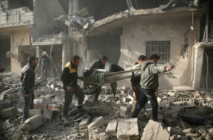 Au milieu des destructions, des secouristes évacuent une victime des raids du régime à Arbine dans la Ghouta orientale près de Damas, le 8 février 2018