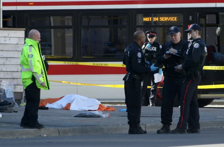 Des policiers près d'un corps caché par un drap, le 23 avril 2018 à Toronto, au Canada, après qu'un homme au volant d'une camionnette a fauché une dizaine de piétons