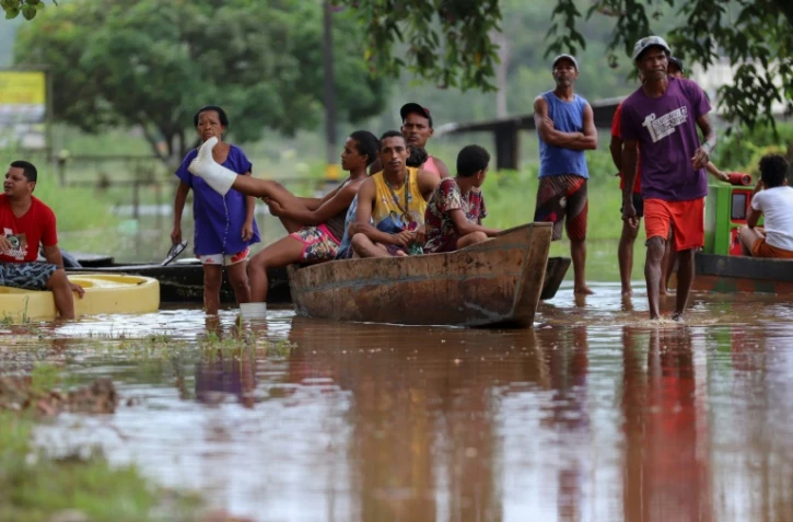 Des habitants utilisent une barque pour traverser un zone inondée dans le quartier Joaia do Atlantico, à Ilheus, dans le sud de l'Etat  brésilien de Bahia