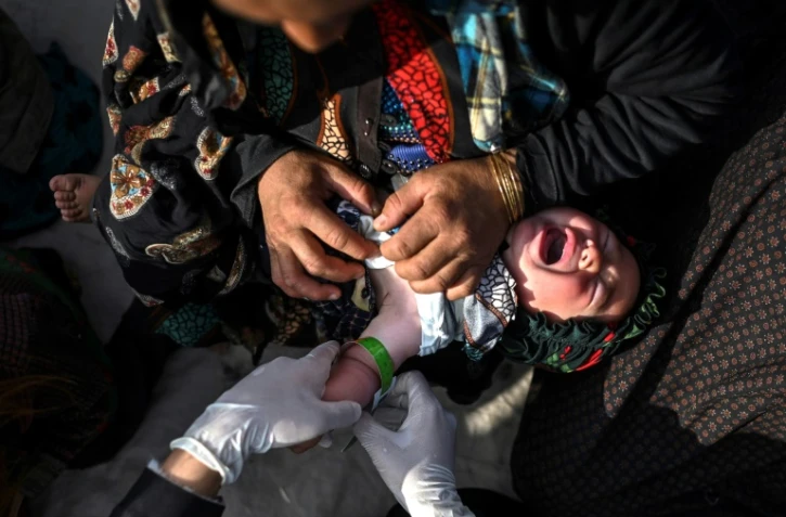 Un membre du personnel de Médecins sans frontières (MSF) observe les signes de malnutrition d'un enfant dans un camp de personnes, près de Hérat, le 22 novembre 2021 en Afghanistan