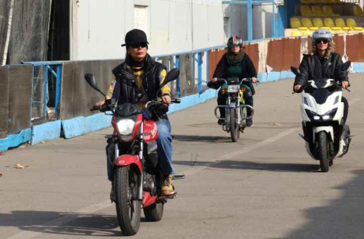 La monitrice Maryam Ghelich (g) guide les élèves Elham (c) et Mona sur leurs scooters dans un centre d'entraînement du nord de Téhéran, le 7 décembre 2025 en Iran
