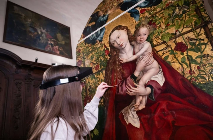 Une experte travaille à la restauration de "La Vierge au buisson de roses" peinte en 1473 par Martin Schongauer, le 5 mars 2026 dans l'église des Dominicains à Colmar, dans le Haut-Rhin