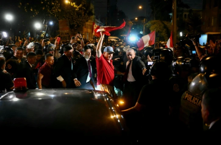 Rafael Lopez Aliaga (au centre), candidat à la présidence du Pérou, agite le drapeau national péruvien pendant un rassemblement devant le siège du Jury national des élections (JNE) à Lima, le 14 avril 2026