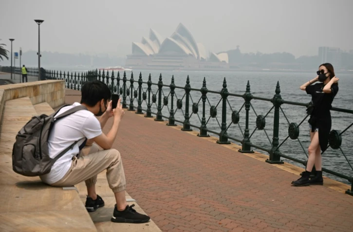 Des touristes portent des masques en raison des fumées toxiques liées aux incendies de forêts, le 10 décembre 2019 à Sydney, en Australie