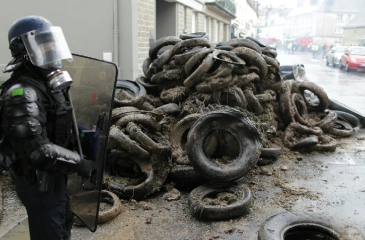 Un policier devant des pneus brûlés par des agriculteurs qui manifestent contre la baisse des prix de leurs produits à Saint-Lô, le 2 février 2016-