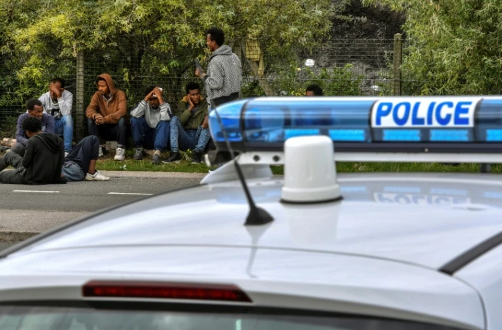 Une voiture de police et des migrants près du port de Calais, le 16 août 2017