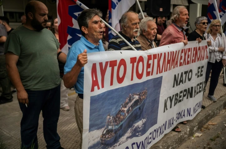 Des manifestants devant le tribunal de Kalamata, en Grèce, avec une bannière "Ils sont coupables de ce crime" à l'ouverture du procès de neuf Egyptiens accusés d'être impliqués dans l'un des naufrages de migrants les plus meurtriers en Méditerranée, le 21 mai 2024