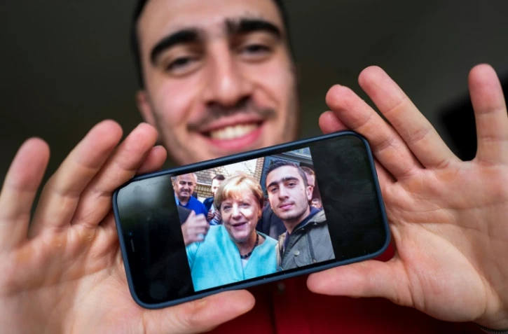 Anas Modami, réfugié Syrien, montre le selfie qu'il a pris avec Angela Merkel en septembre 2015, le 1er septembre 2021 dans son appartement de Berlin