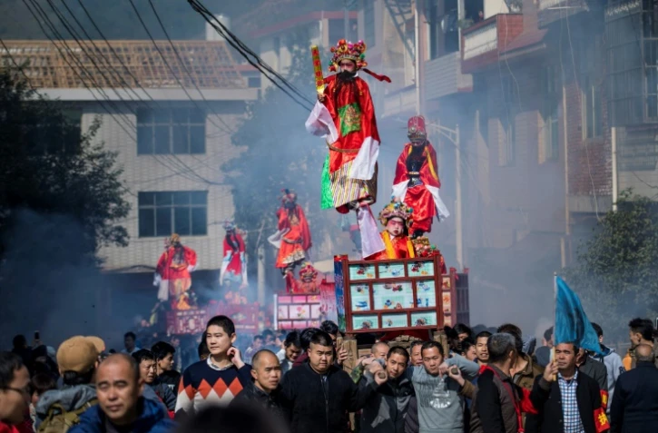 Des enfants, maquillés et habillés de costumes bordés et colorés, en parade, debout sur des palanquins, dans les rues de Luofang, le 11 février 2017 dans l'est de la Chine
