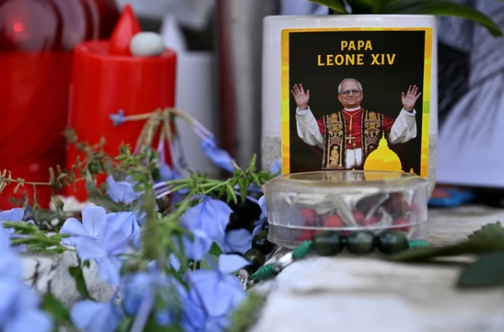 Des fleurs, des bougies et une photo du pape Léon XIV déposées au pied de la statue de Jean-Paul II, devant l’hôpital Gemelli à Rome où le pape Léon XIV est en convalescence, le 17 octobre 2026
