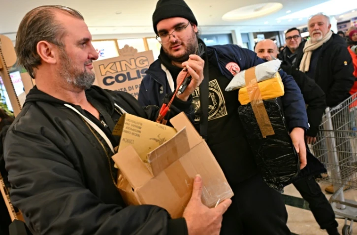 Des acheteurs lors d'une "vente à l'aveugle" de colis non réclamés, où les boîtes de toutes tailles sont vendues au poids dans un centre commercial de Rome, le 17 janvier 2025