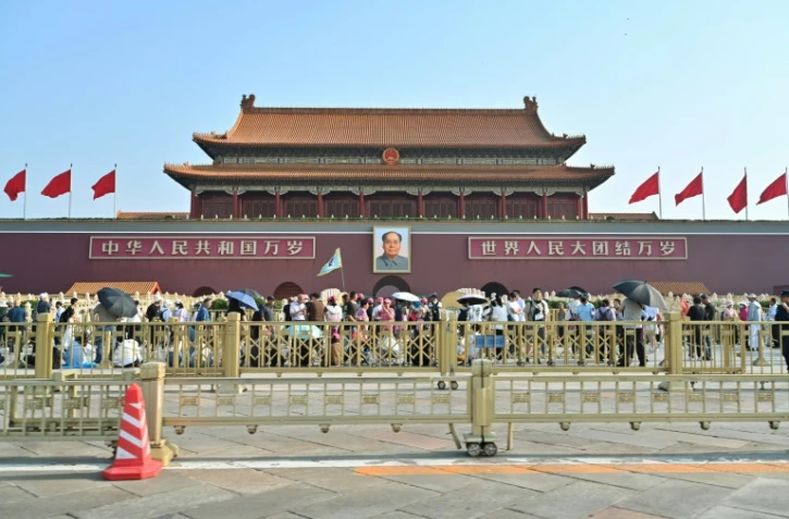 Des personnes marchent devant le portrait de Mao Tsé-toung sur la place Tiananmen, le 4 juin 2024 à Pékin
