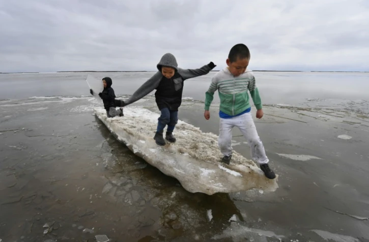 Des enfants jouent sur un bloc de glace en train de fondre dans le village eskimo yupik de Napakiak, le 18 avril 2019 en Alaska