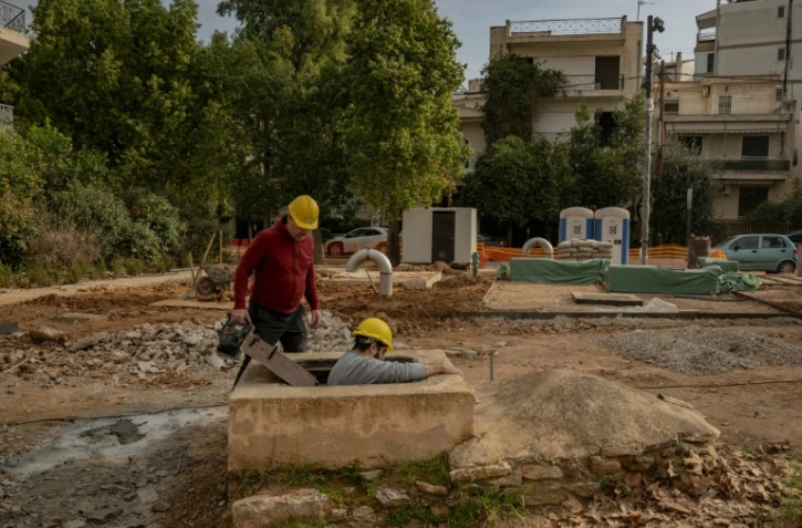 Christos Geovanopoulos (g), responsable du projet de l'aqueduc d'Hadrien à la municipalité de Halanadri, et Yannis Dafnos, géologue, entrent dans un bassin de décantation faisant partie de l'aqueduc d'Hadrien, à Chalandri, dans la banlieue d'Athènes, le 27 janvier 2025