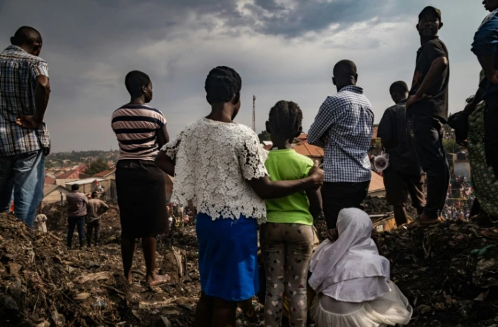 Des habitants assistent aux recherches des secours après l'effondrement d'une décharge à Kampala, le 10 août 2024 