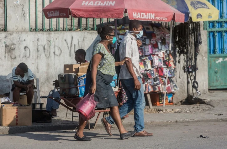 Des personnes portent un masque de protection contre le coronavirus dans une rue de Port-au-Prince, le 26 mars 2020 Ă HaĂŻti