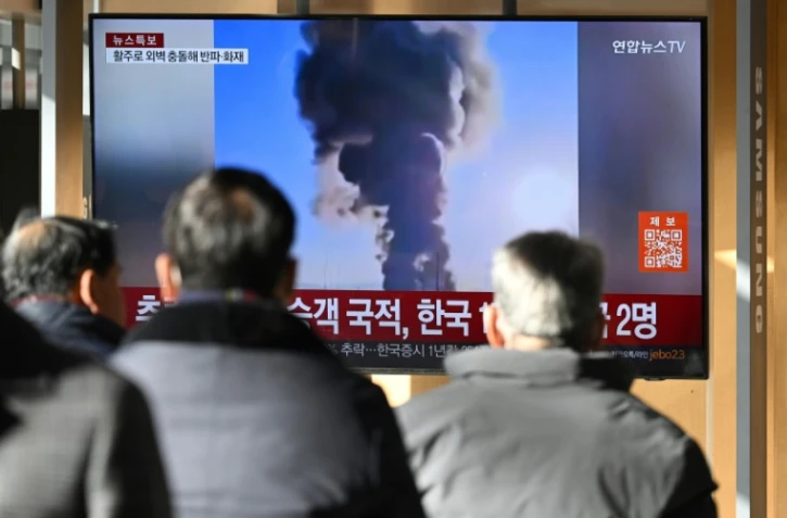 Des gens regardent les images de l'accident d'avion à l'aéroport international de Muan, dans une gare de Séoul, le 29 décembre 2024