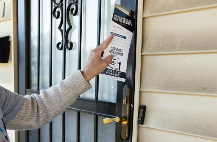Une militante pour la protection du droit à l'avortement laisse un prospectus en faveur du "oui" à la porte d'une maison à Columbus, dans l'Ohio le 5 novembre 2023