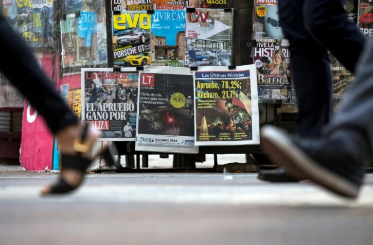 Des personnes passent devant un kiosque affichant les couvertures des journaux au lendemain du référendum lors duquel les Chiliens ont voté à une très forte majorité en faveur d'une nouvelle Constitution, le 26 octobre, à Santiago, au Chili