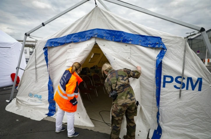 Une employée de l'aéroport d'Orly et une militaire française inspecte une tente équipée pour soigner des patients infectés par le nouveau coronavirus, le 3 avril 2020 au sud de Paris