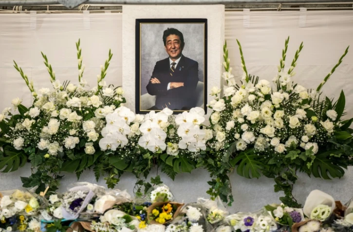 Des fleurs déposées devant un portrait de l'ancien Premier ministre japonais Shinzo Abe lors d'une cérémonie dans un temple, un an après sa mort, le 8 juillet 2023 à Tokyo

