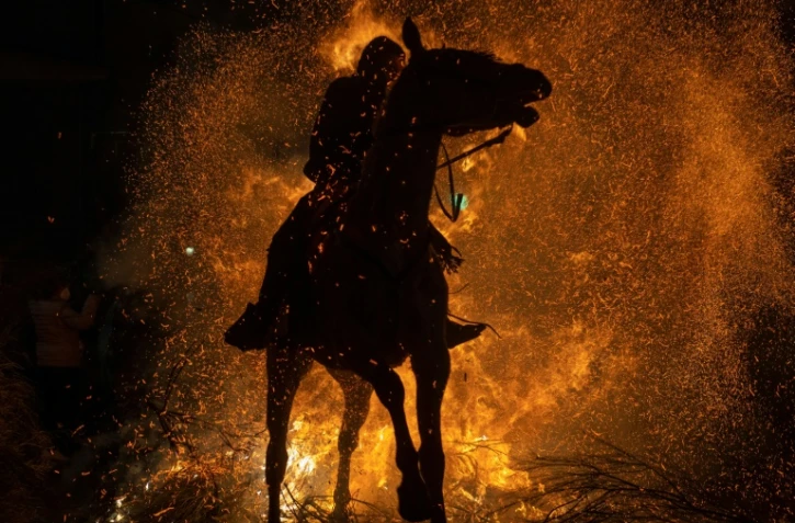 Un cheval et son cavalier traversent un brasier dans le village espagnol de San Bartolome de Pinares pour les traditionnelles "Luminarias", le 16 janvier 2022