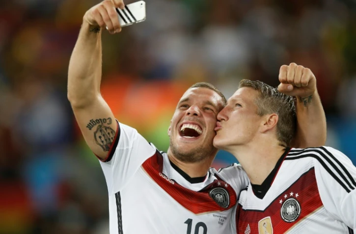 Bastian Schweinsteiger (d) et Lukas Podolski font un selfie après la victoire de la Mannschaft face à l'Argentine en finale du Mondial, le 13 juillet 2014 à Rio 
