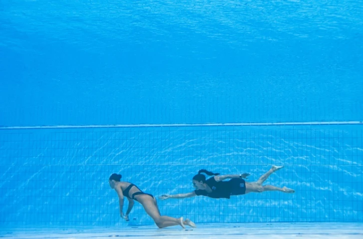 L'entraîneure de l'équipe américaine de nage artistique et synchronisée Andrea Fuentes (d) vient sauver sa nageuse Anita Alvarez qui a perdu connaissance lors des Mondiaux de natation, à Budapest, le 22 juin 2022