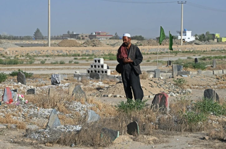 Photo prise le 1er juin 2025 près de kaboul de Gul Ajan Hotak priant sur la tombe de son défunt fils Shafiullah Hotak, mort après être tombé d'un avion C-17 de l'armée de l'air américaine pour fuir le pays dirigé par les talibans 