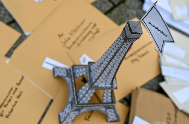 Une tour Eiffel en carton couronnée d'un drapeau: "Fais en sorte que Paris devienne une réalité" faite partie d'une installation posée par des activistes face à la porte de Brandenburg à Berlin le 11 décembre pour marquer les 5 ans de l'Accord de Paris sur le climat