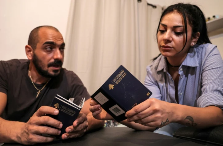 Nanor Abachian (d) et son mari Shadi Abi Haidar regardent leurs passeports, chez eux, à Beyrouth, le 31 août 2021 au Liban