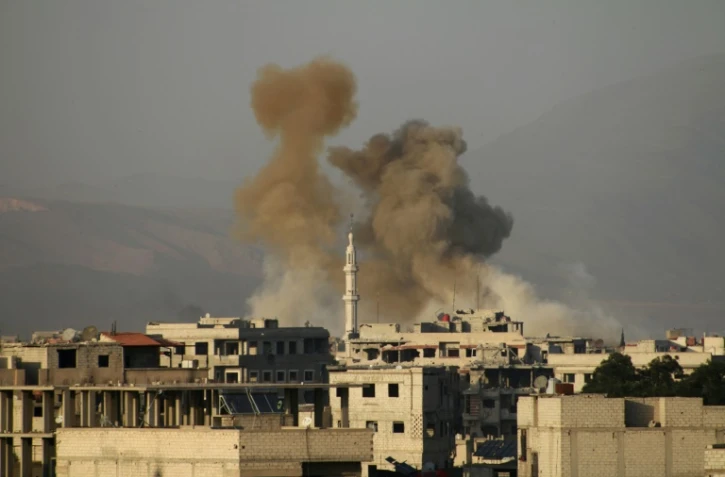 De la fumée s'élève après un bombardement du régime au-dessus de la ville sous contrôle rebelle de Saqba, dans la Ghouta orientale, près de Damas, le 11 mars 2018