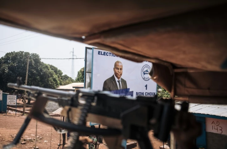 Des casques bleus égyptiens patrouillent dans Bangui, devant une affiche électoral du président Faustin Archange Touadéra, le 25 décembre 2020