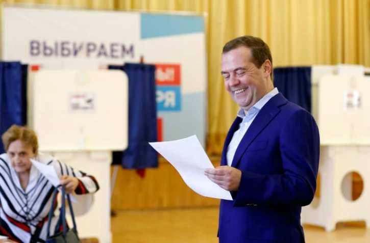 Le Premier ministre russe Dmitri Medvedev sourit en tenant un bulletin dans un bureau de vote à Moscou, le 9 septembre 2018
