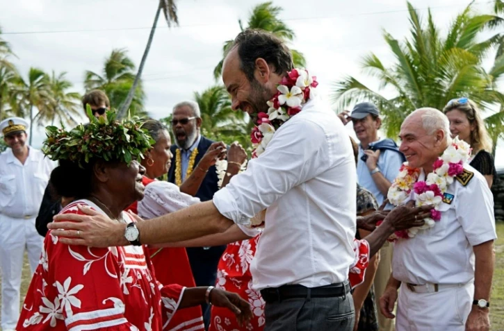 Le Premier ministre Edouard Philippe (d) reçoit un collier de fleurs lors d'une cérémonie de bienvenue sur l'île de Tiga, le 3 décembre 2017 en Nouvelle-Calédonie