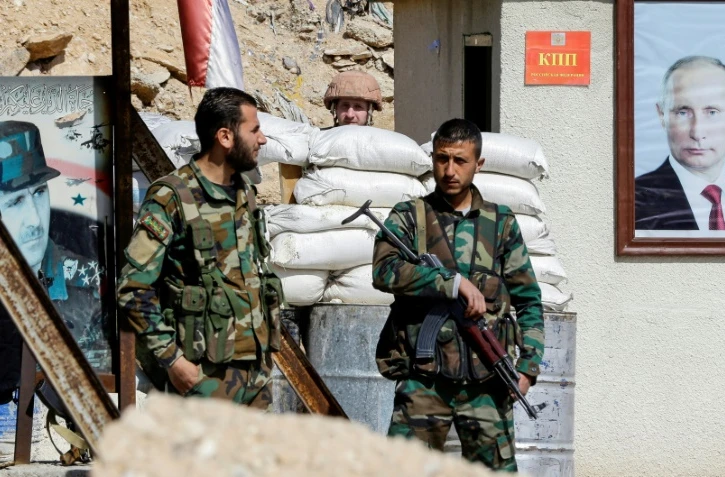 Des forces progouvernementales syriennes devant des portraits des présidents russe et syrien, Vladimir Poutine et Bachar al-Assad, au passage d'Al-Wafidine à la limite de la Ghouta orientale, le 1er mars 2018