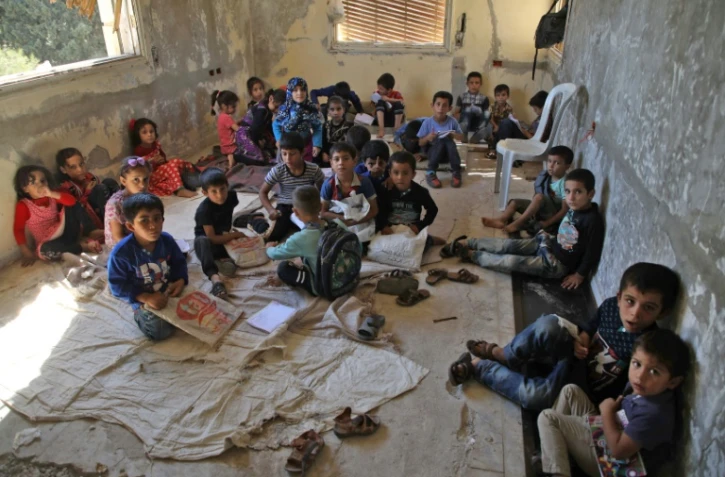 Des enfant syriens déplacés suivent des cours dans une villa abandonnée transformée en école, dans les territoires rebelles d'Alep dans le nord-ouest de la Syrie, le 24 septembre 2018