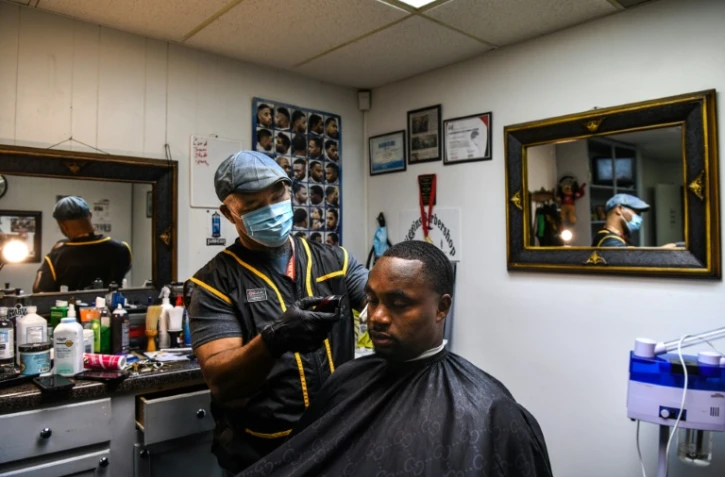 Antonio Wiggins (G) coupe les cheveux de James Bennett dans son salon, à Jackson, le 26 septembre 2020