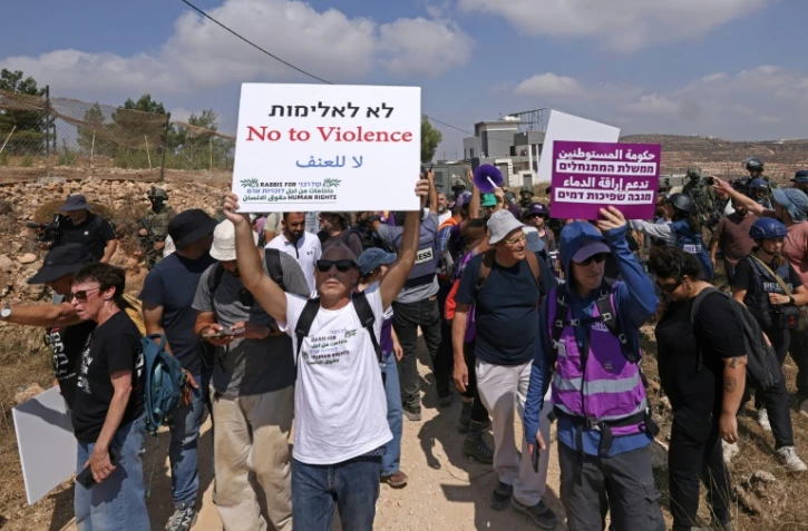 Des militants israéliens et des bénévoles solidaires rassemblés devant une maison palestinienne assiégée par des colons israéliens dans le village de Qusra, au sud de Naplouse, en Cisjordanie occupée, le 14 août 2026