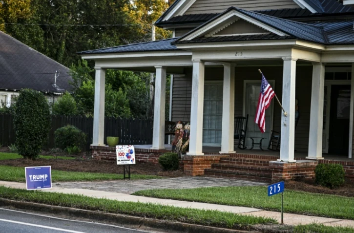 Une pancarte pro-Trump et une autre marquant le centième anninversaire de l'ancien président américain Jimmy Carter devant une maison de Plains (Géorgie, sud-est), le 30 septembre 2024