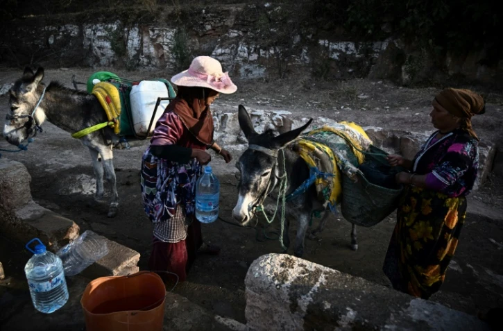 Des habitants tirent l'eau d'un puits pour remplir des bidons dans le village d'Ihermane,, après un puissant séisme, le 13 septembre 2023 au Maroc