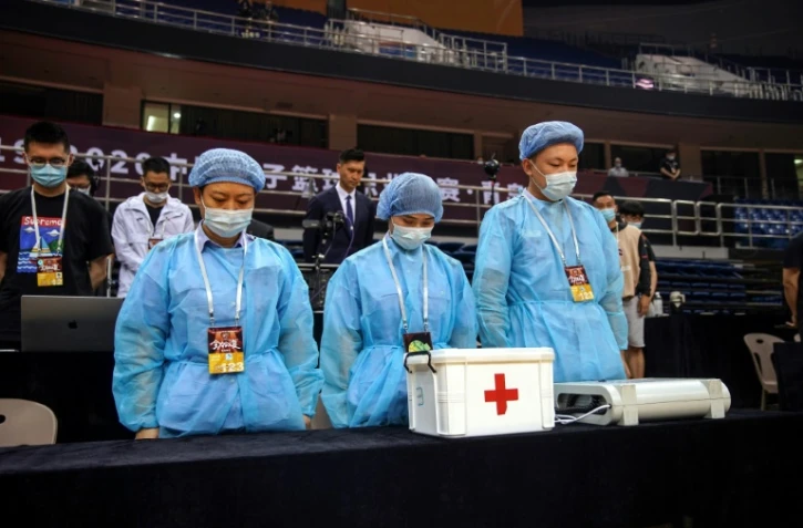 Du personnel soignant rend hommages aux morts du coronavirus avant un match de basketball Ă Qingdao, le 20 juin 2020