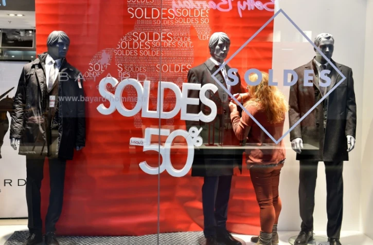 Une jeune femme met la dernière main à l'installation d'une vitrine à l'occasion du lancement des soldes, à Talange (Moselle), le 2 janvier 2018