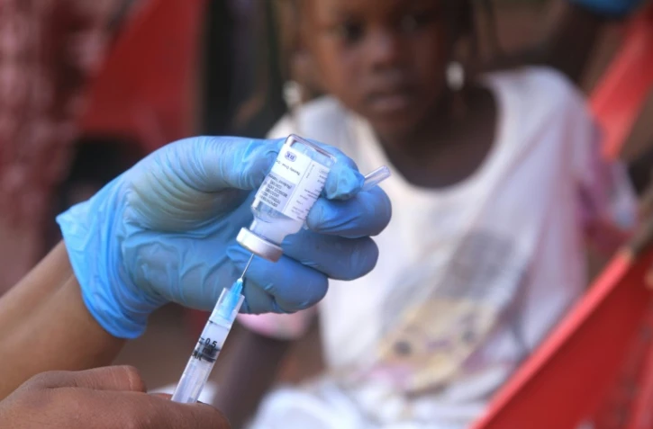 Un enfant soudanais observe la préparation d'un vaccin lors d'une campagne de vaccination contre la diphtérie dans un camp de déplacés dans la ville d'Al-Dabbah, dans le nord du Soudan, le 22 novembre 2025