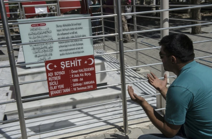Un homme prie devant la tombe d'Omer Halisdemir, célèbre "martyr" du putsch manqué du 15 juillet 2016, le 10 juillet 2017 au cimetière de Cukurkuyu, en Turquie