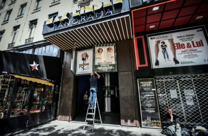 Des employés retirent d'anciennes affiches sur la devanture du cinéma Max Linter à Paris, le 18 juin 2020