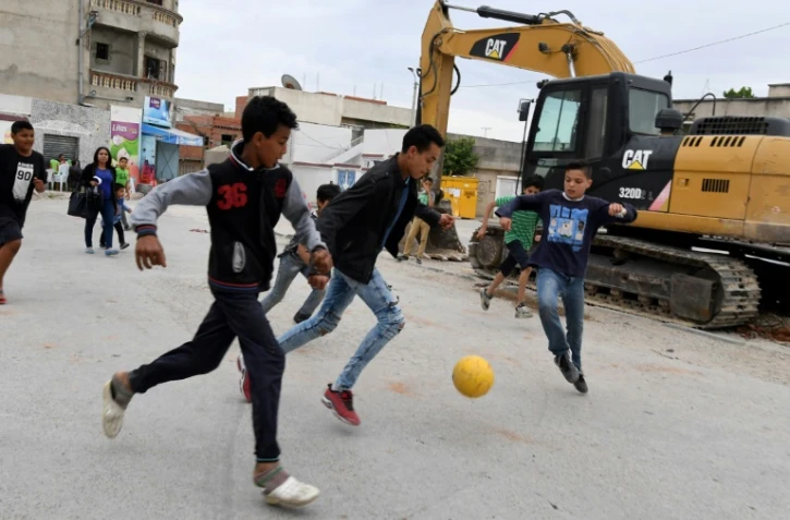 Des enfants jouent au football dans une rue du quartier populaire d'Ettadhamen, en banlieue de Tunis, le 30 avril 2018